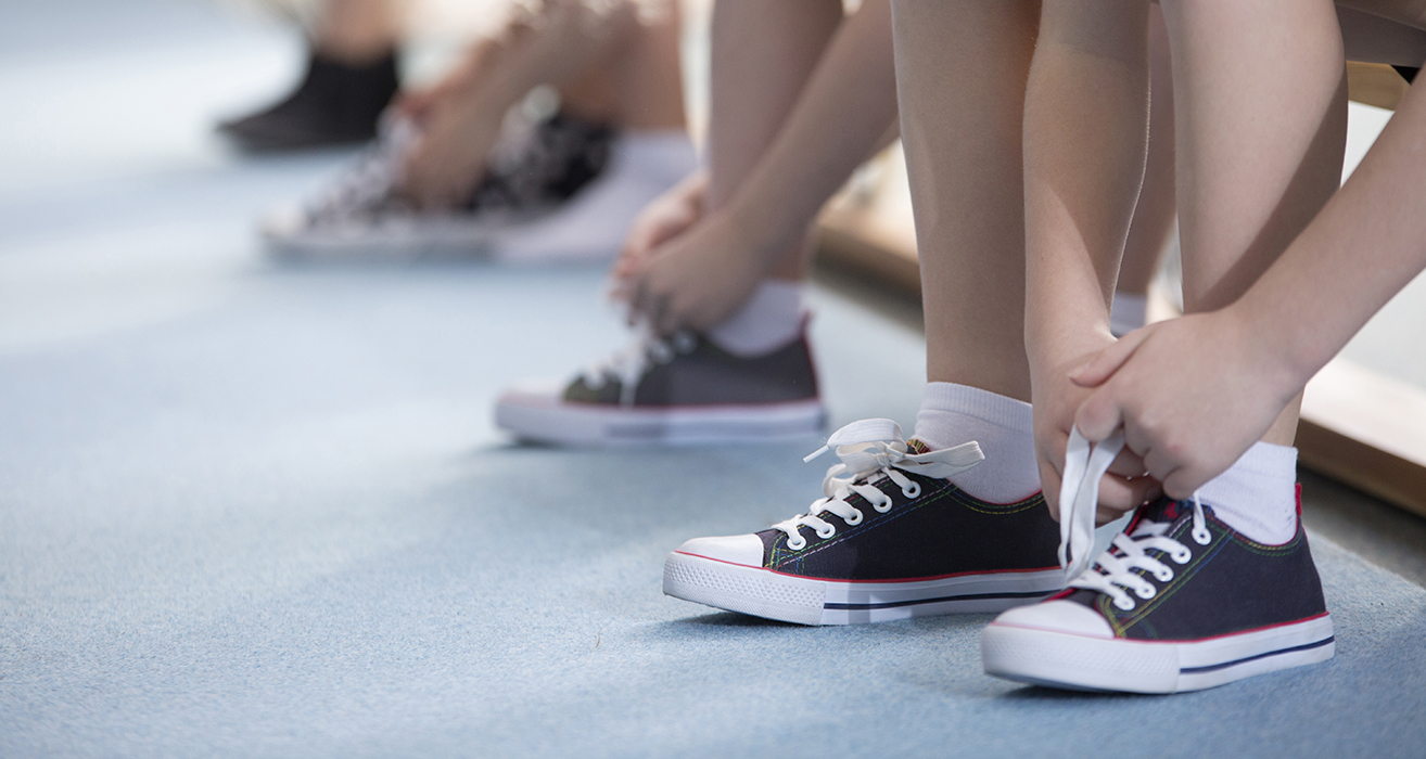 Des élèves lacent leurs chaussures de basket.